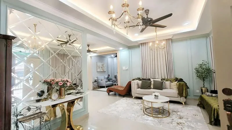 Living features: chandelier with multiple bulbs, 5-blade ceiling fan, sofa with green and white cushions, coffee table with round top, area rug with geometric pattern, decorative wall mirror, wall-mounted curtains, green accent chair, decorative plant in pot, golden side table, wall paneling with light blue color, recessed ceiling lights; style: modern.
