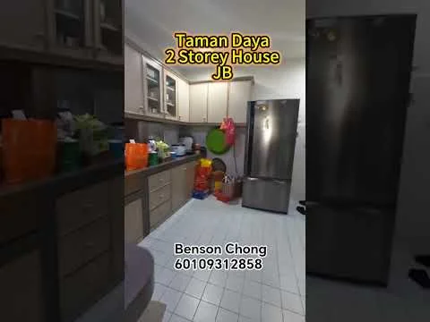 Kitchen features: light wood cabinetry, stainless-steel fridge, white tiled flooring, green circular cutting board, various colored plastic storage containers, multiple bags and boxes on the floor, glass-front upper cabinets, countertop with space for appliances.