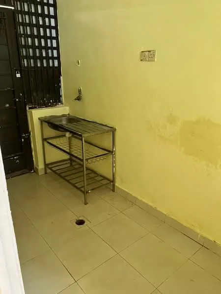 Room features: yellow painted walls, ceramic tile flooring, stainless-steel work table with shelves, wall-mounted faucet, drainage hole in floor, metal security grille on window, light switch, power outlet.