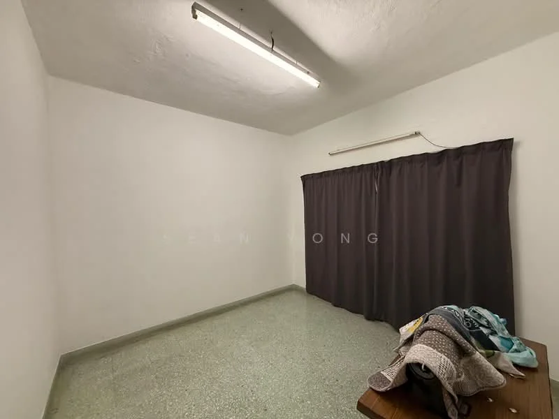 Room features: white painted walls, green terrazzo flooring, curtains in dark grey, fluorescent ceiling lights, wooden table, folded blankets or textiles on table.