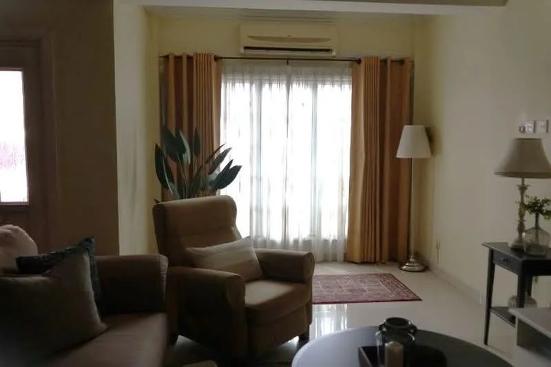 Living features: beige fabric armchair, brown fabric sofa, round coffee table, area rug with geometric pattern, floor lamp, curtains in mustard yellow, floor-to-ceiling windows, white walls, recessed ceiling lights, potted plant; style: contemporary.