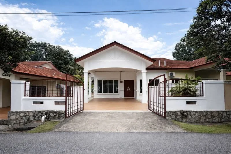 Exterior type: detached bungalow; features: white painted facade, red tiled roof, stone cladding at base, gated entrance, manicured lawn, surrounded by greenery, driveway with concrete surface, two wall-mounted split AC units, front porch area, decorative iron gate; style: modern.