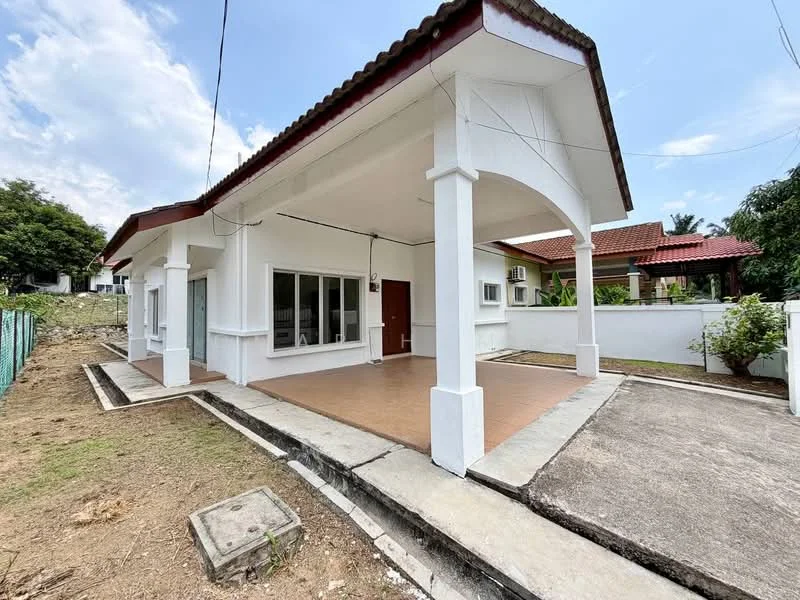 Exterior type: detached bungalow; features: white painted facade, red tiled roof, covered porch area, large windows, concrete flooring, surrounded by greenery, fenced yard, single-storey, driveway, landscaped garden area; style: modern.