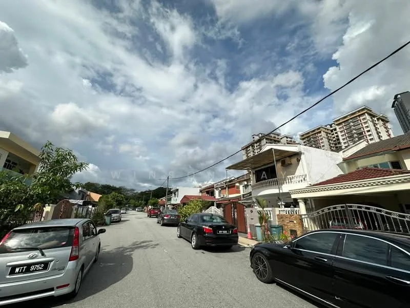Exterior type: linked terrace house; features: two-storey linked terrace houses, driveway with interlocking pavers, manicured lawns, street lined with parked cars, surrounded by mature greenery, cloudy sky, urban residential street; style: modern.