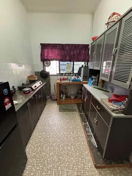 Kitchen features: black refrigerator, grey cabinetry with louvered doors, granite countertop, white tiled backsplash, sink with faucet, stove with exhaust hood, wooden kitchen island, mosaic tile flooring, window with purple curtain, kitchen utensils on countertop, decorative items on shelves.