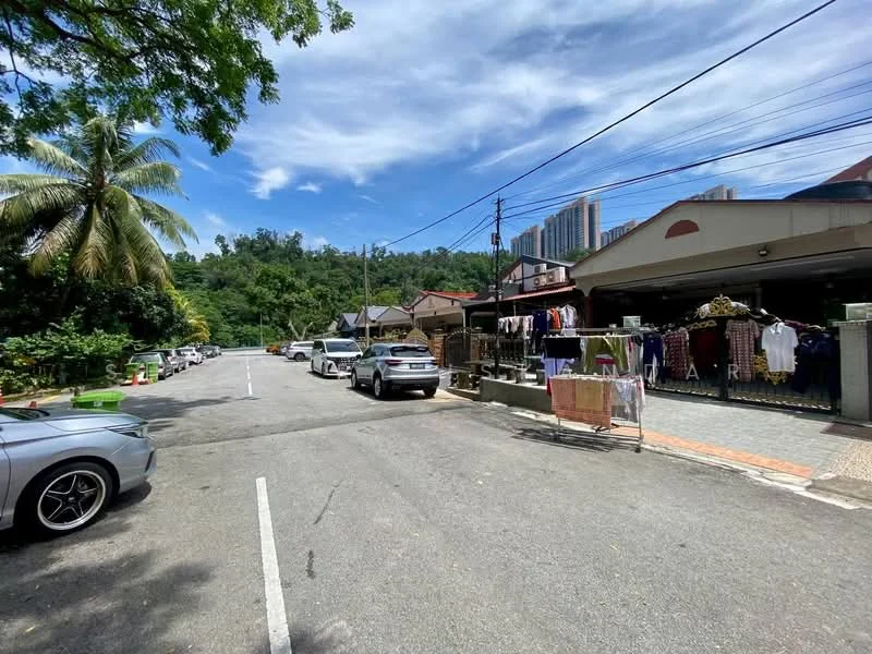 Exterior features: paved road, palm trees, residential buildings in background, multiple parked cars, laundry hanging on a line, greenery in surrounding area, clear blue sky.