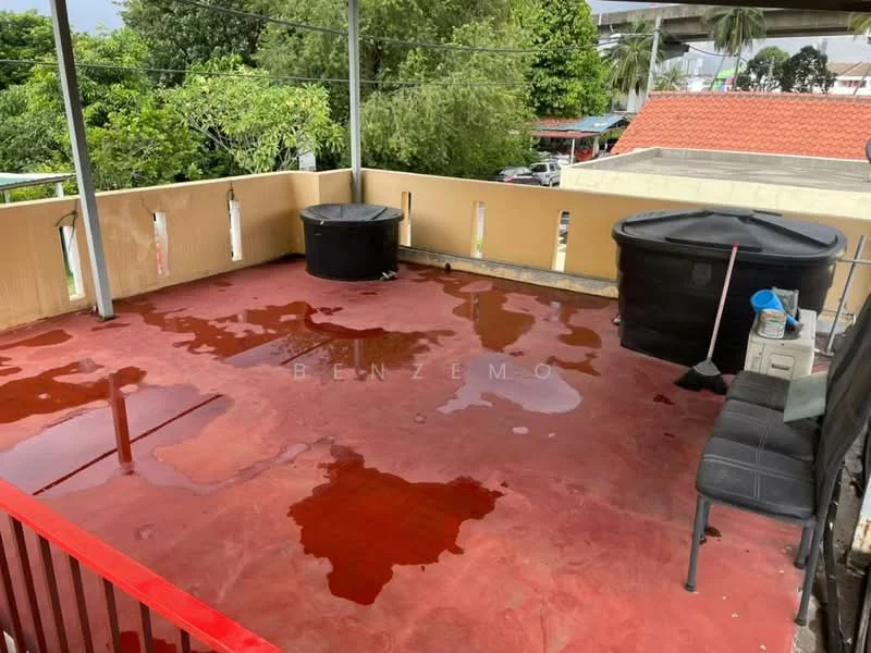 Exterior features: open terrace, red painted flooring, black water tanks, metal railing, surrounded by greenery, partial roof cover, outdoor seating area.