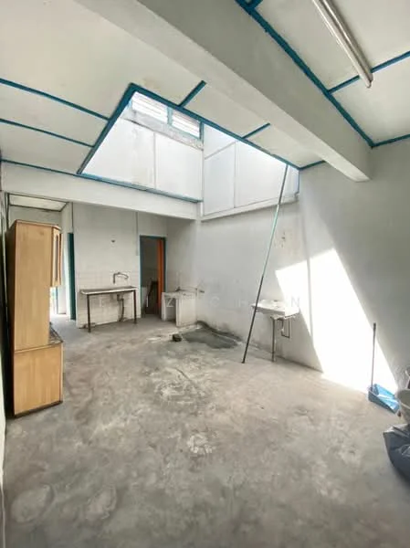 Room features: concrete flooring, grey painted walls, exposed ceiling with blue beams, single-bowl stainless-steel sink, wooden cabinet, worktable, natural light from skylight, doorway leading to another room; style: industrial.