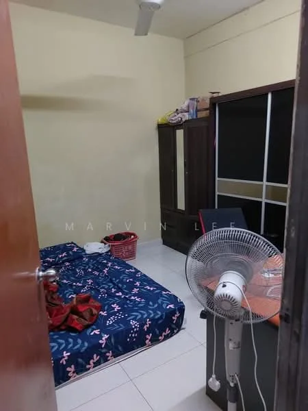 Bedroom features: single bed with patterned bedding, wooden wardrobe with sliding doors, desk with chair, table fan, white tiled flooring, plain painted walls, basket for storage.