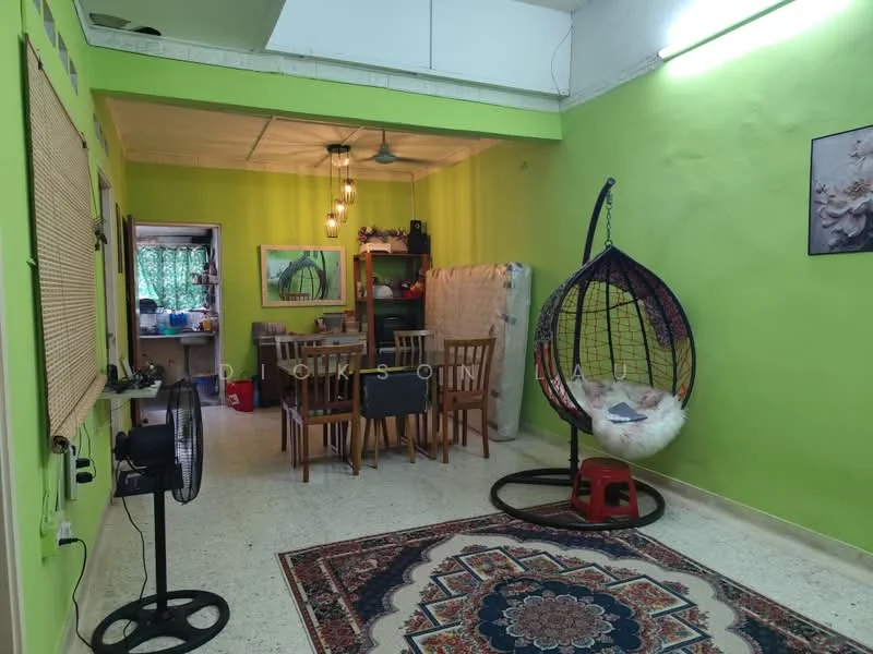 Living features: green painted walls, exposed ceiling, hanging pendant lights, hanging rattan egg chair, wooden dining table with chairs, area rug with intricate pattern, fan, wooden shelving unit, framed artwork, open layout to kitchen, decorative wall art; style: modern. Kitchen features: open layout, kitchen counter, wooden cabinets, stainless-steel sink, kitchen appliances visible; style: modern.