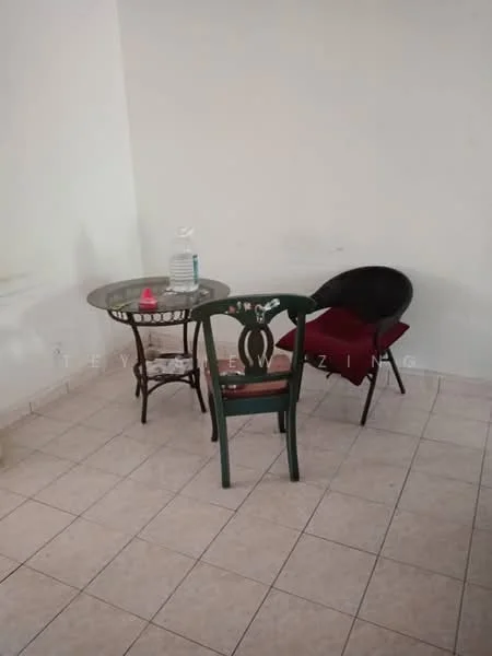 Room features: square tile flooring, white painted walls, glass-top round table, green wooden chair, black round chair with cushion, bottle of water on table, red cushion on chair; style: minimalist.