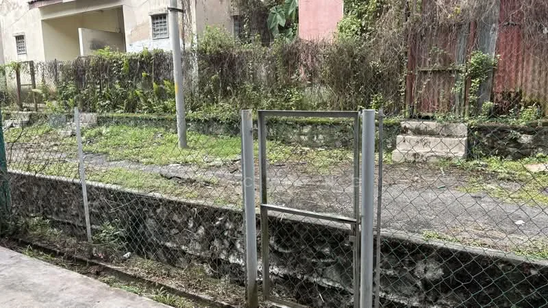 Exterior features: chain-link fence, metal gate, overgrown vegetation, paved pathway, concrete retaining wall, dilapidated building in background, grassy area, dirt path.