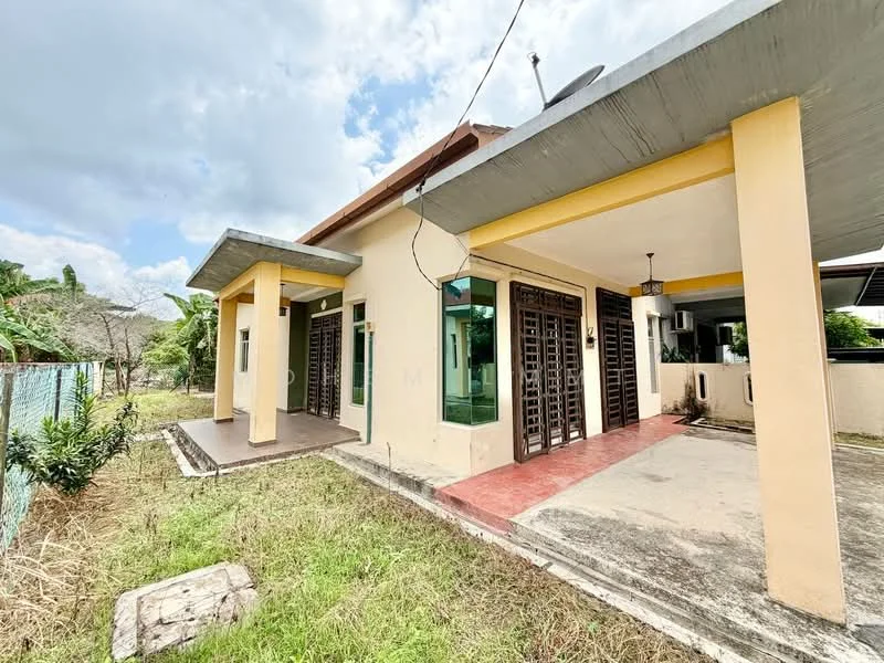 Exterior type: detached bungalow; features: single-storey, concrete facade, yellow painted columns, large glass windows, covered porch area, sloped roof, manicured lawn, surrounded by greenery, driveway, outdoor lighting fixture; style: modern.