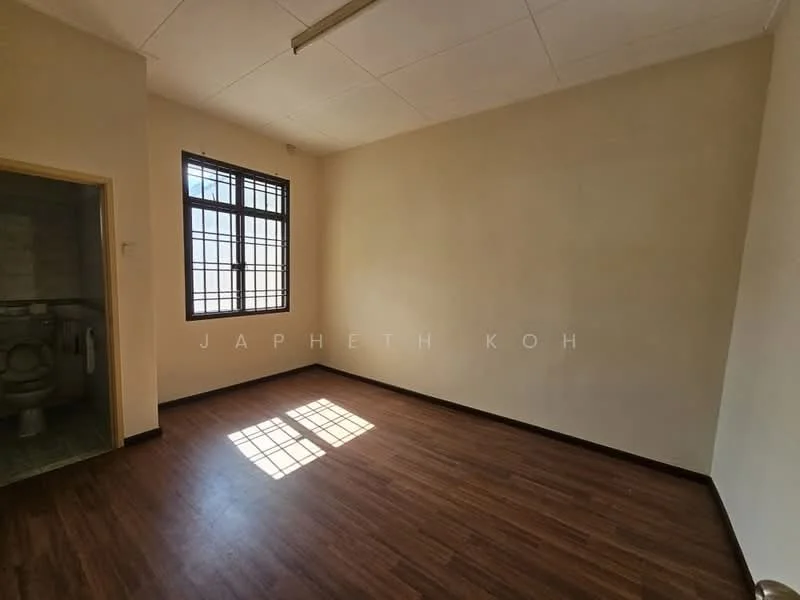 Room features: light brown laminate flooring, white painted walls, large window with black metal grille, natural light from window, ceiling light fixture, corner with bathroom door, no visible furniture, plain ceiling; style: minimalist.