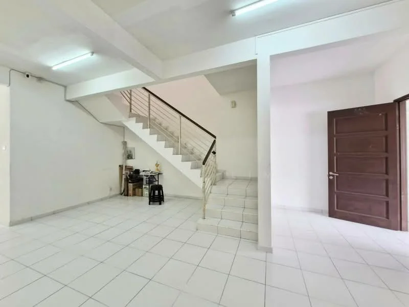 Room features: white painted walls, white tiled flooring, staircase with metal railing, single wooden door, ceiling lights, open layout, corner space for furniture, no visible decor; style: minimalist.