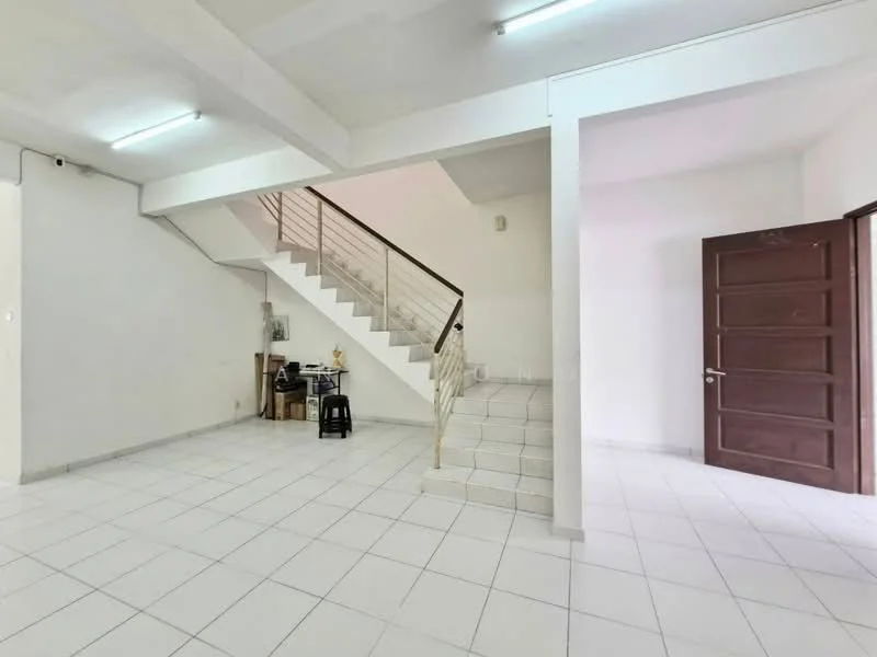 Room features: white painted walls, white tiled flooring, staircase with metal railing, door with wooden finish, ceiling lights, open layout, corner space for furniture, no visible appliances or fixtures; style: minimalist.