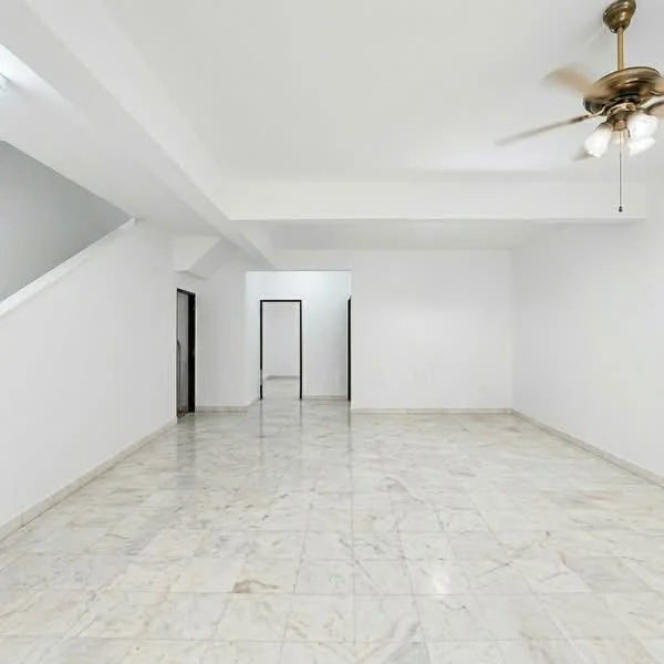 Living features: white painted walls, marble tile flooring, 5-blade ceiling fan with light, large open space, natural light from windows, staircase visible in background, no visible furniture, neutral color palette; style: modern.