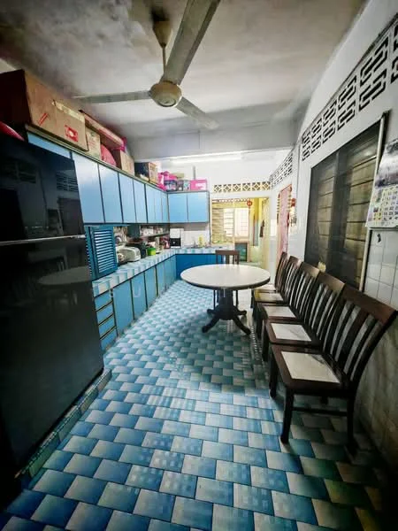 Kitchen features: blue cabinetry, white countertop, round dining table, wooden dining chairs, black refrigerator, stainless-steel sink, ceiling fan, tiled flooring with blue and white pattern, wall-mounted shelves, window with metal grille, various kitchen appliances, open layout.