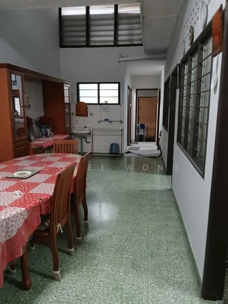 Dining features: red and white checkered tablecloth, wooden dining table with six chairs, green terrazzo flooring, wall-mounted cabinets, window with metal grilles, decorative wall art, open layout to hallway, light fixture on ceiling. Hallway features: green terrazzo flooring, white painted walls, windows with metal grilles, doorway leading to another room, light fixture on ceiling.