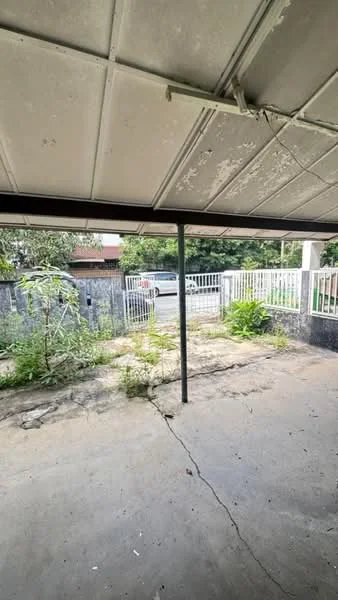 Exterior type: car porch; features: concrete flooring, metal support beams, fenced perimeter, overhead roof, surrounding greenery, driveway access, visible street view; style: minimalist.