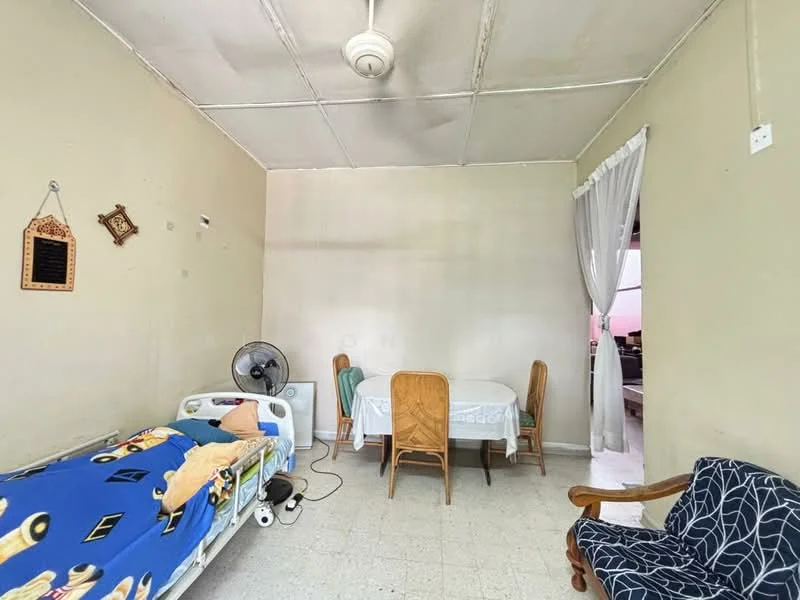 Room features: light-colored painted walls, ceiling with tiles, ceiling fan, table with four wooden chairs, single bed with blue bedding, wooden armchair, flooring with tiles, curtain at doorway; style: minimalist.