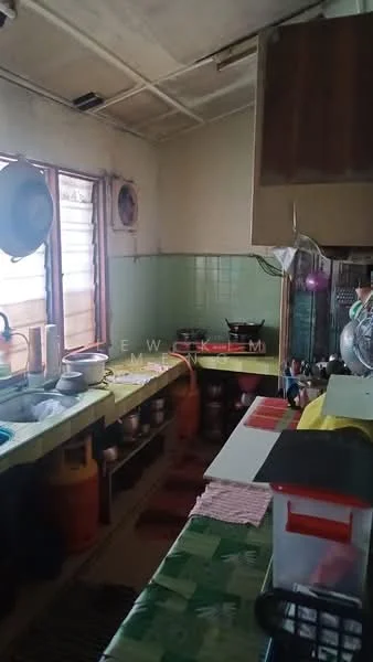 Kitchen features: green tiled walls, wooden cabinetry, laminate countertop, single-bowl stainless-steel sink, chrome pull-down faucet, gas stove, exhaust fan, open shelving, flooring with patterned vinyl, window with wooden frame, various cooking pots and utensils, gas cylinder, dish rack; style: traditional.