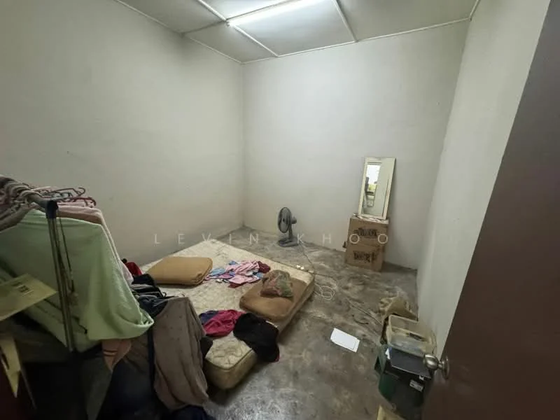 Room features: bare concrete flooring, white painted walls, ceiling fan, full-length mirror, mattress on the floor, clothing on a rack, clothing on the floor, cardboard box, plastic storage container; style: minimalist.