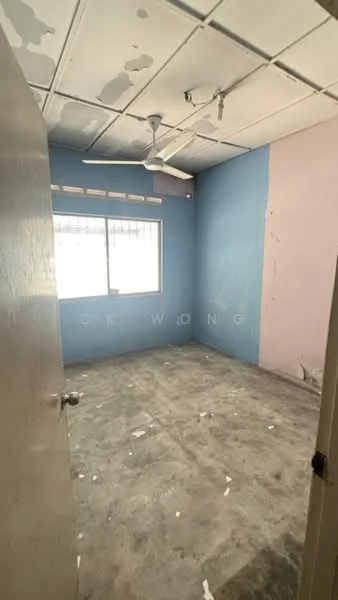 Room features: blue painted walls, pink painted wall, ceiling fan, window with grille, concrete flooring, exposed ceiling, light fixture, door, scattered debris.