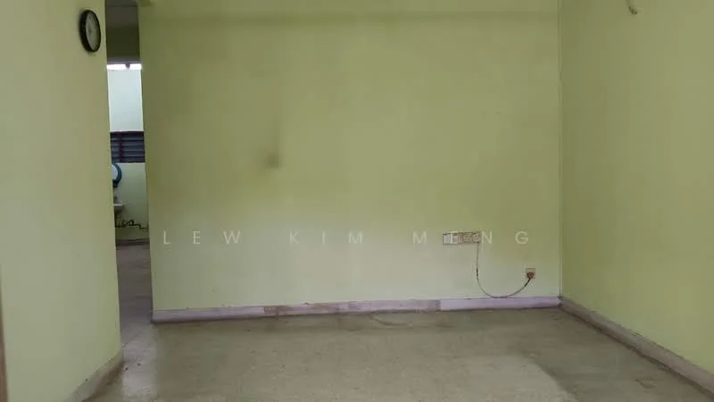 Room features: light green painted walls, bare concrete flooring, single light fixture on ceiling, wall socket, empty space.