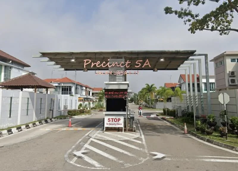 Exterior type: gated community; features: main entrance gate, security guard house, paved driveway, landscaped greenery, surrounding residential buildings, stop sign, overhead shelter, traffic cones; style: modern.