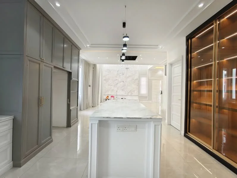 Kitchen features: marble countertop, grey cabinetry, white cabinetry, recessed downlights, pendant lights, high-gloss tile flooring, built-in shelving, feature wall with textured finish, floor-to-ceiling windows, curtains, island with storage, open layout; style: modern.