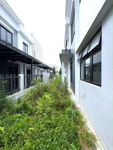 Exterior type: linked terrace house; features: white painted facade, black framed windows, concrete pathway, overgrown greenery, side garden area, two-storey structure, metal awning, fenced boundary; style: modern.