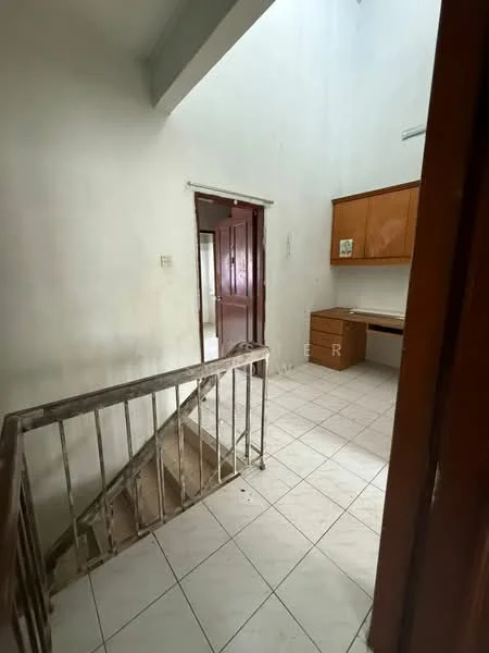 Room features: white painted walls, tile flooring, staircase with metal railing, wooden cabinetry, desk area, doorway leading to another room, high ceiling, natural light from upper window.