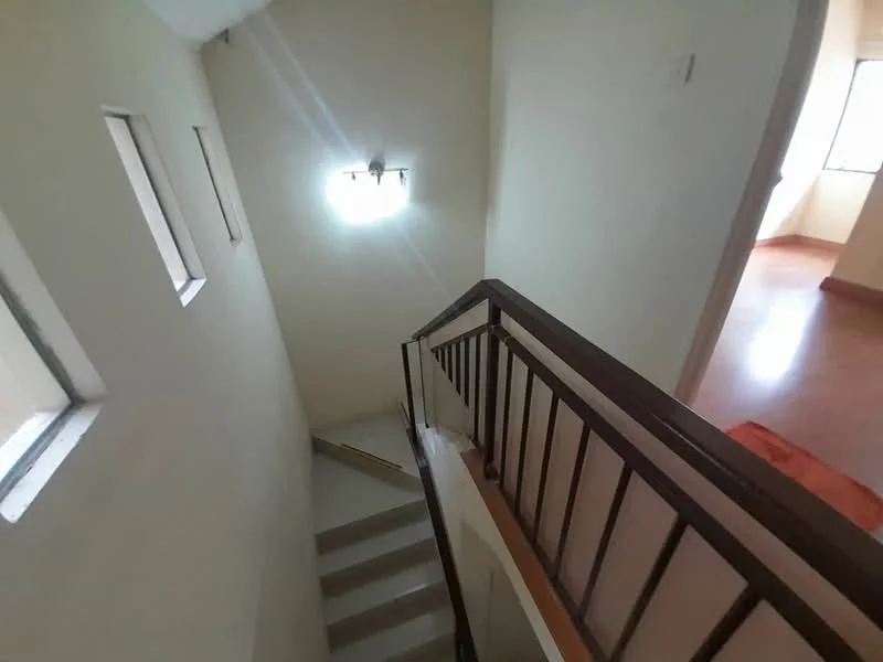 Room features: white painted walls, staircase with metal railing, natural light from windows, light fixture on ceiling, concrete flooring, small windows, open space, neutral color scheme; style: modern.