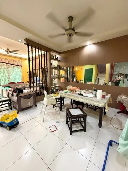 Living features: white tiled flooring, yellow painted walls, ceiling fan, wooden partition, large mirror on wall, dining table with chairs, high chair, various decorative items on shelves, curtains with floral pattern, multiple light sources, cluttered space with various items.