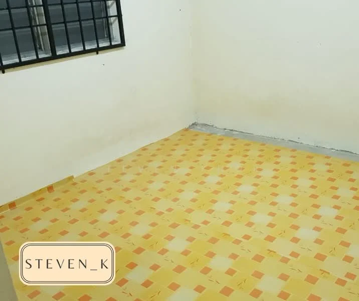 Room features: yellow and orange checkered tile flooring, plain white painted walls, window with black metal grille, concrete floor base.