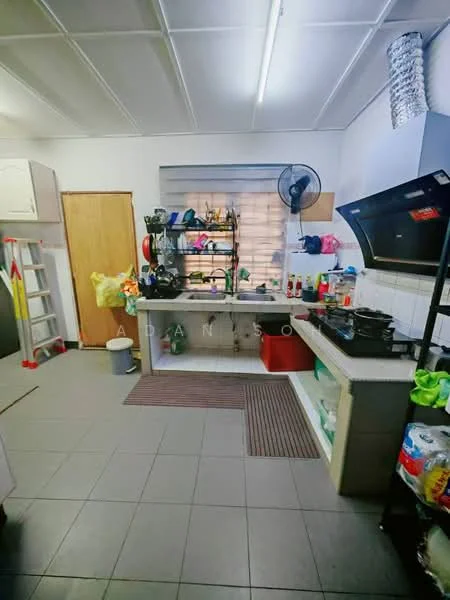Kitchen features: white cabinetry, stainless-steel sink, black gas stove, exhaust hood, open shelving, wall-mounted fan, grey tiled flooring, countertop with storage underneath, various kitchen appliances, ladder against the wall, red plastic container, cleaning supplies, kitchen mats; style: functional.