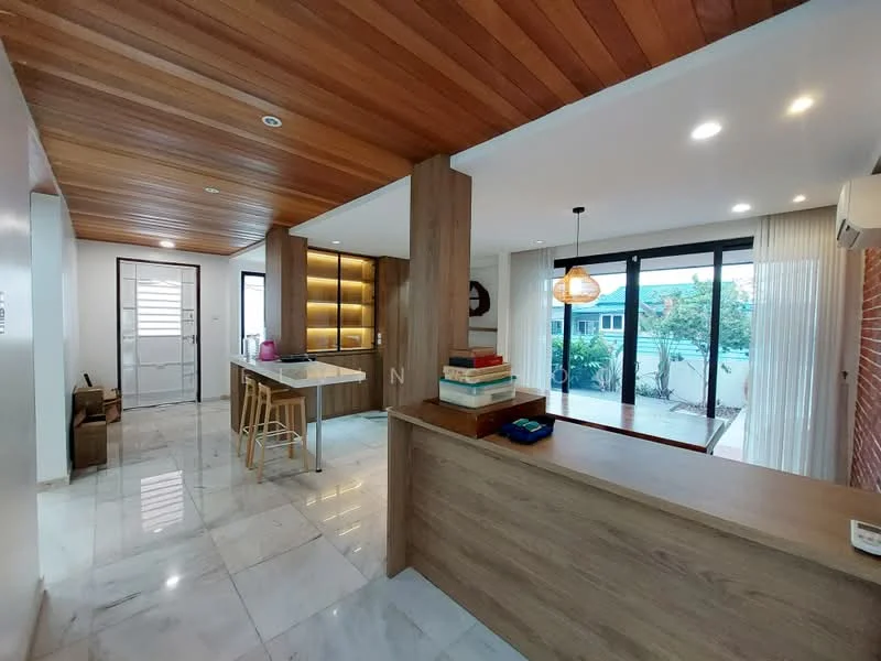 Living features: wooden ceiling with recessed lighting, marble tile flooring, large sliding glass doors, brick accent wall, built-in wooden cabinetry, open layout, bar counter with stools, natural light from windows, decorative wall light; style: modern; view: garden.