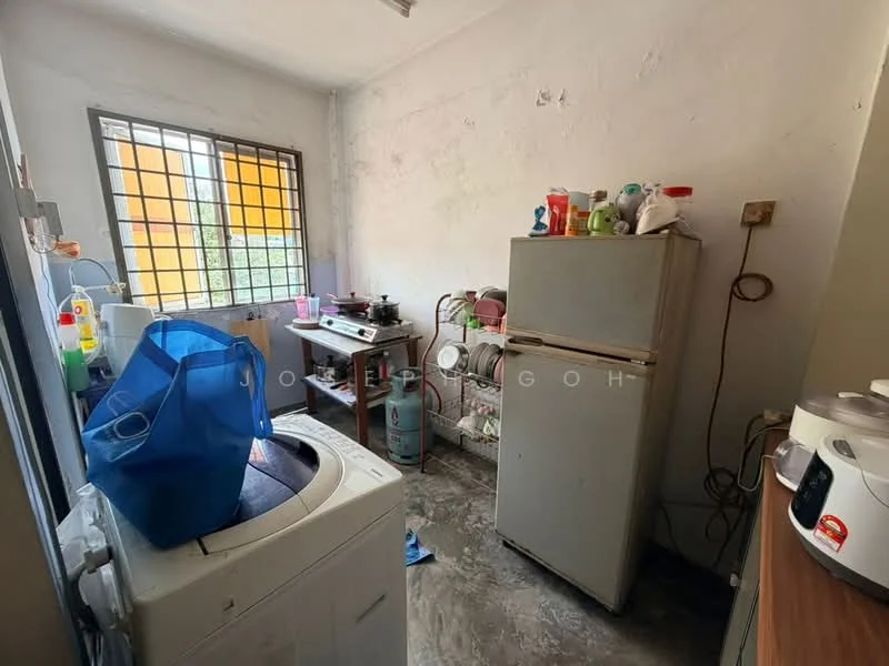 Laundry features: washing machine, fridge, wooden countertop, grey concrete flooring, window with metal grille, various cleaning supplies on shelves, gas stove, plastic storage containers, sink, wall-mounted electrical outlet.
