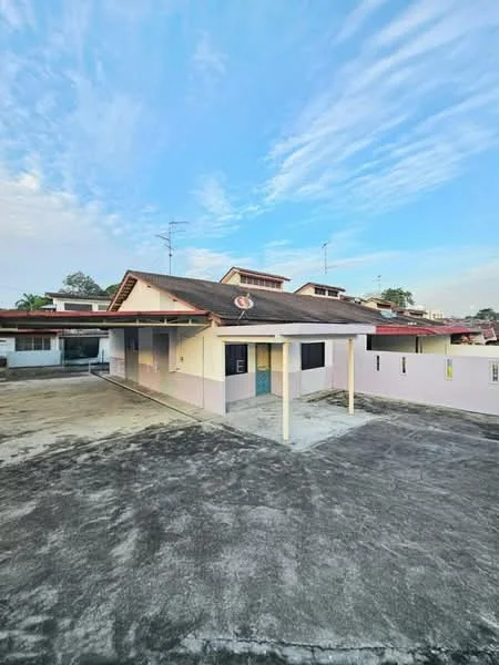 Exterior type: detached bungalow; features: single-storey building, pitched tile roof, cream painted facade, pink accent walls, concrete driveway, surrounded by open space, visible antenna on roof, clear blue sky, manicured lawn in background; style: traditional.