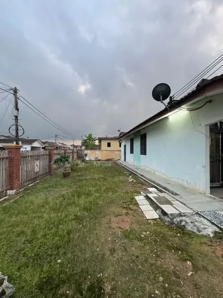 Exterior type: detached bungalow; features: grass lawn, fenced yard, paved walkway, satellite dish, exterior wall painted in light blue, single-storey structure, utility poles visible, cloudy sky; style: traditional.