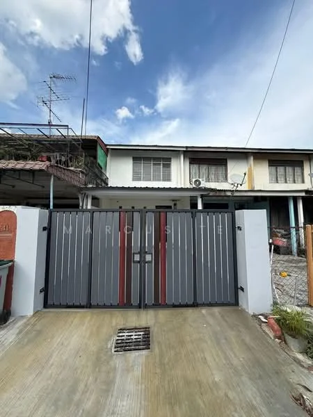 Exterior type: linked terrace house; features: grey painted facade, double-volume main entrance gate, concrete driveway, visible air conditioning unit, manicured lawn, surrounded by residential buildings, metal gate with red accents, roof overhang, satellite dish on roof; style: modern.