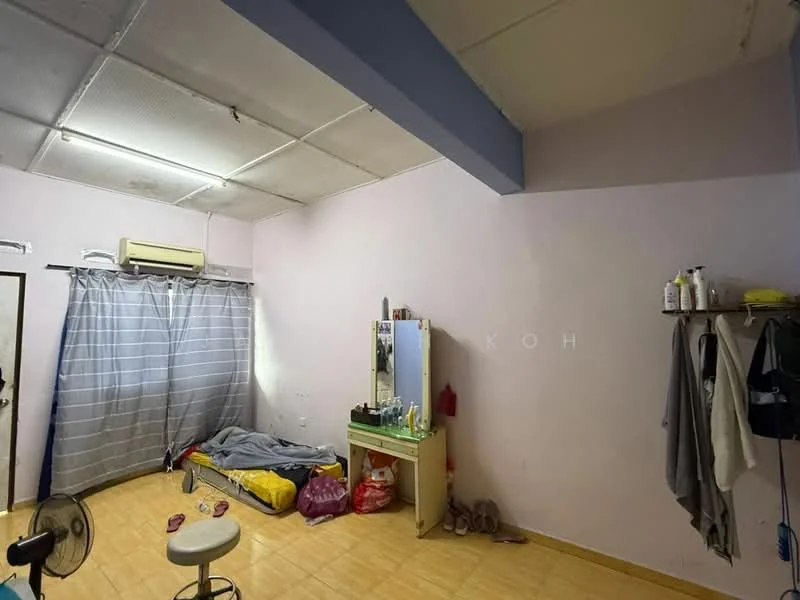 Room features: light purple painted walls, vinyl flooring, ceiling with exposed beams, window with sheer curtains, 1 wall-mounted split AC, folding screen, bed with bedding, dressing table, mirror, clothes rack, fan, plastic bags.