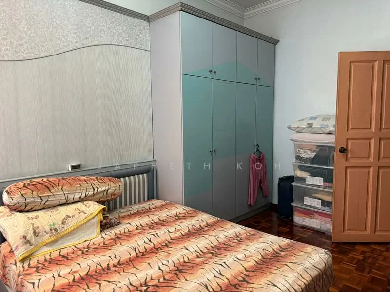 Bedroom features: queen-size bed with patterned bedding, built-in wardrobe with sliding doors, wooden flooring, decorative wall paneling, window with sheer curtains, nightstand, plastic storage drawers, clothes hanging on wardrobe.