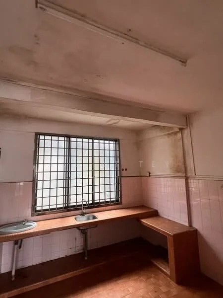 Room features: two single-bowl stainless-steel sinks, wooden countertop, pink tiled backsplash, white painted walls, brown tiled flooring, metal window grilles, fluorescent ceiling lights, exposed ceiling, no visible appliances.