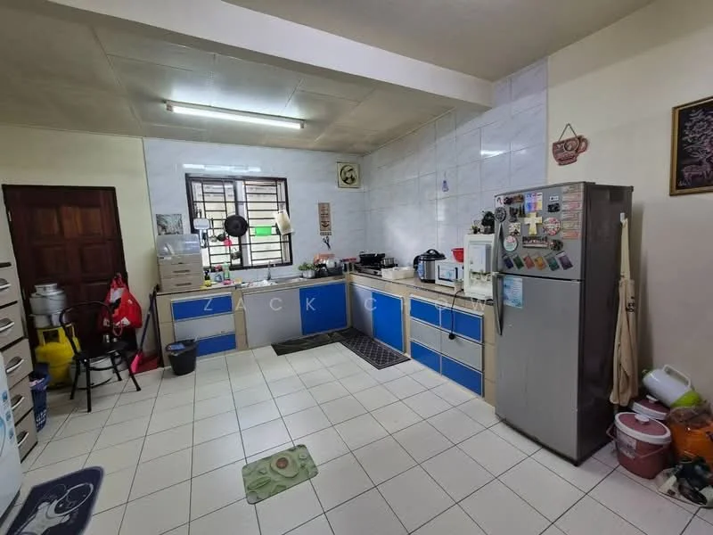 Kitchen features: white tiled walls, light grey ceiling, ceramic tile flooring, blue cabinetry with white countertops, stainless-steel fridge, freestanding gas stove, microwave, kitchen sink, window above sink, wall-mounted shelves, decorative wall art, kitchen mat, trash bin, multiple kitchen appliances.