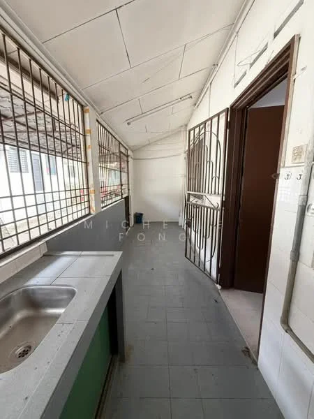 Room features: grey tiled flooring, white walls, metal grilles on windows, single-bowl stainless-steel sink, green cabinetry under sink, door leading to another room, overhead ceiling with panels, light fixture on ceiling.