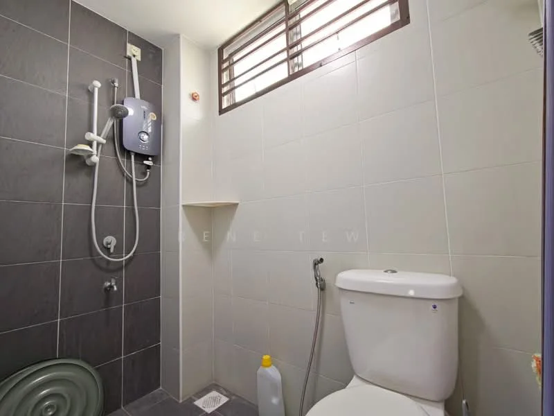 Bathroom features: shower with handheld showerhead, wall-mounted water heater, white toilet, grey ceramic tile flooring, grey wall tiles, white wall tiles, small shelf, window with horizontal bars, cleaning supplies bottle; style: modern.