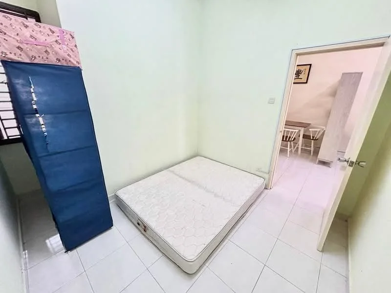 Bedroom features: white painted walls, white tiled flooring, single mattress on bed frame, blue mattress protector, window with black grille, door leading to another room, small dining table with chairs visible through the door.