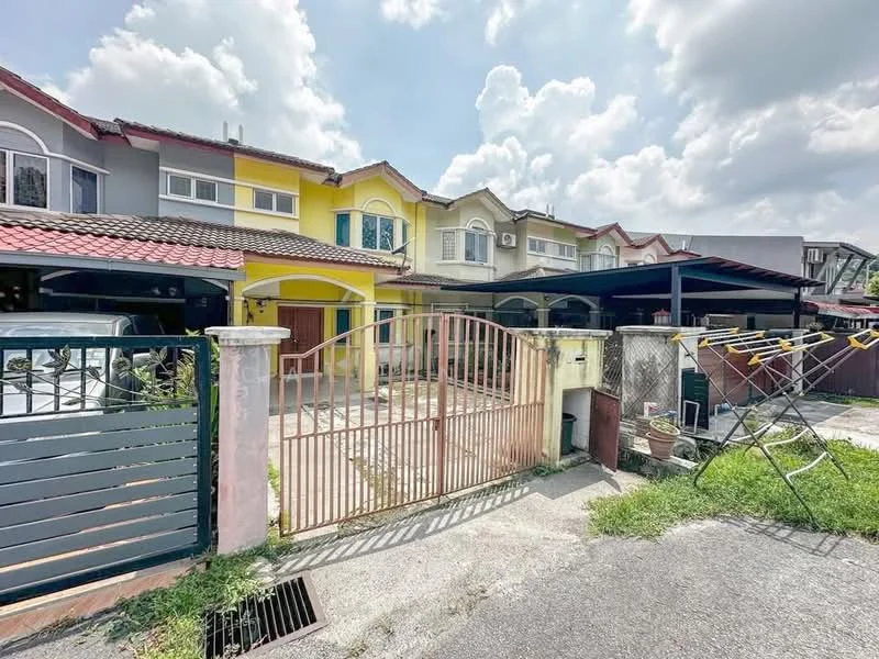 Exterior type: linked terrace house; features: yellow painted facade, red tiled roof, front gate with wrought iron design, paved driveway, car porch with awning, manicured lawn, clothes drying rack, surrounding greenery, two-storey structure, visible air conditioning unit; style: modern.
